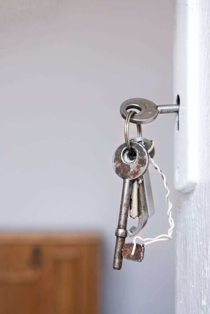 Close-up of vintage keys in a door keyhole with rustic metal and wood textures.
